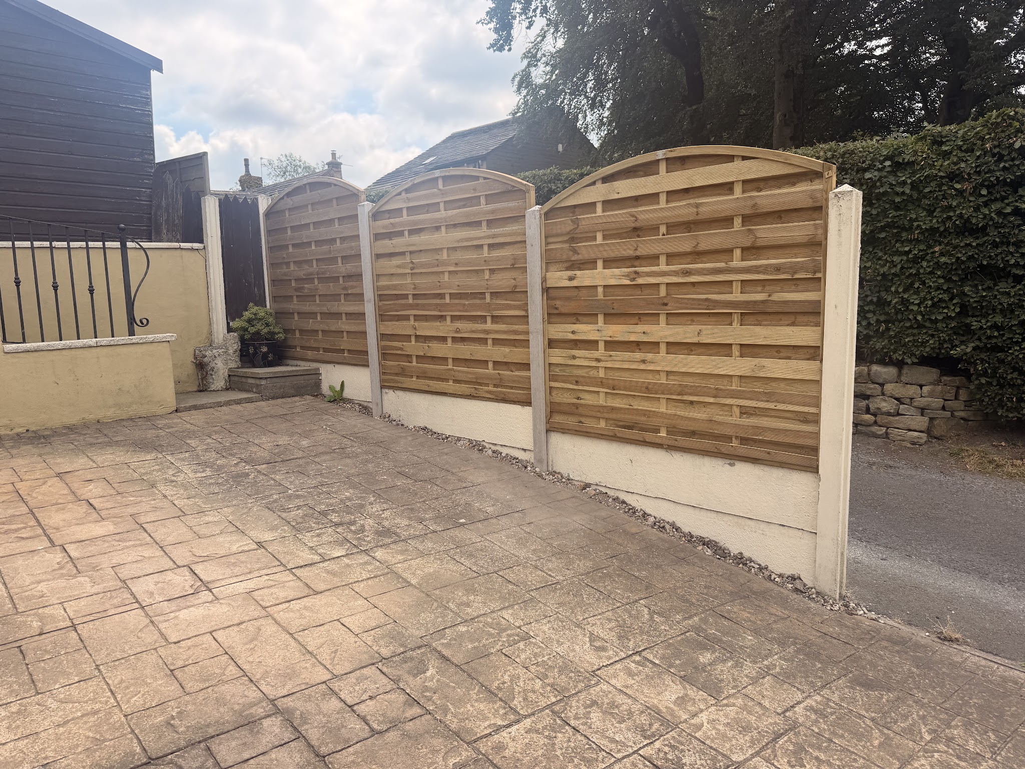New decorative fence panels beside a stamped concrete drive