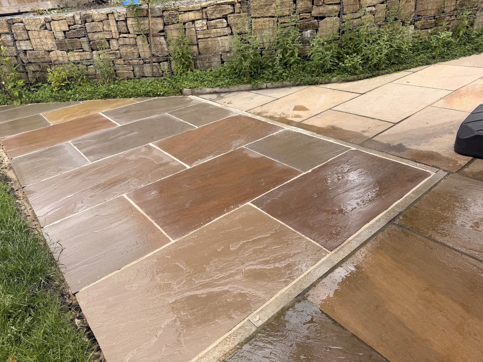 A finished sandstone patio against a dry stone wall